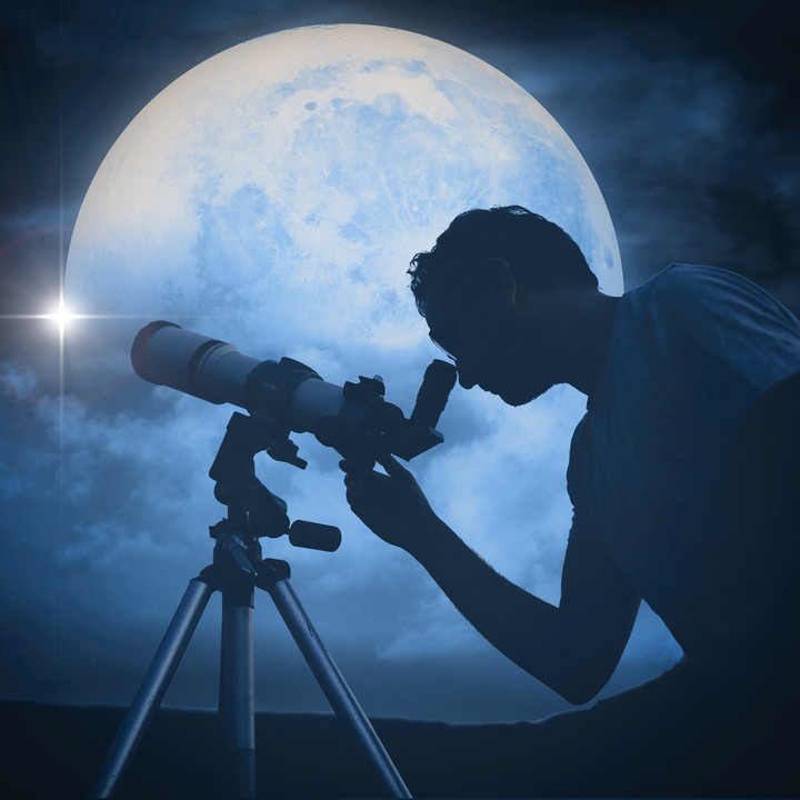 Man looking at the moon through a telescope