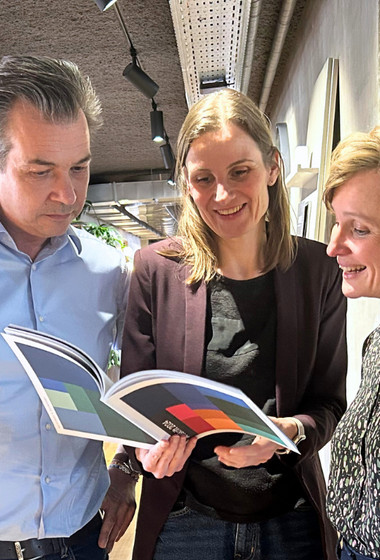 Two men and a woman looking at a document