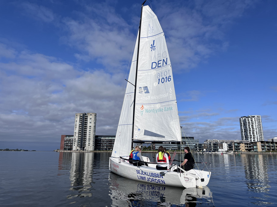 Sailing boat on the water. The sun is shining from a blue sky.